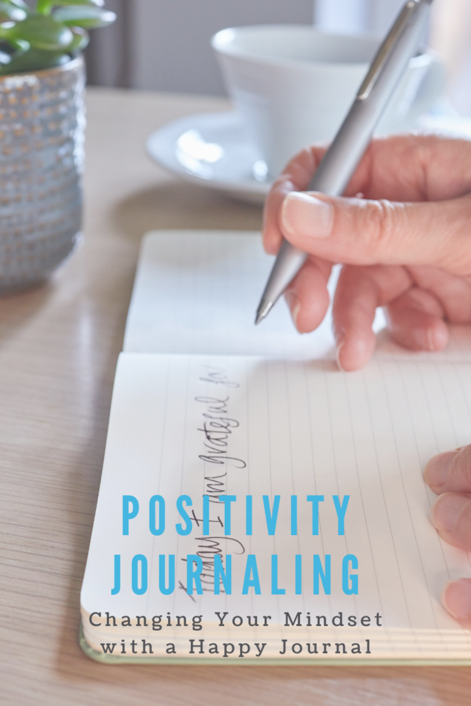 Closeup photo of someone writing in a journal 'today I am grateful for...' with the text overlay "Positivity Journaling: Changing your mindset with a happy journal."